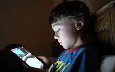 child playing with an iPand in bed